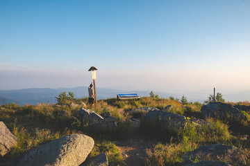 Man stands on a rocky hillside showing a sign. Hiking time in Jeseniky mountains