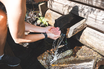 Girl on a hike quenches her thirst with fresh water from a stream originating in the Beskydy...