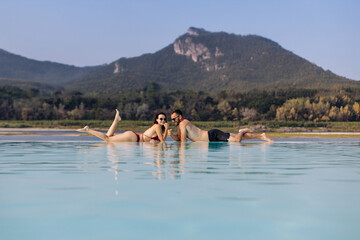Beautiful young couple in an outdoor pool with mountain view. Concept travel, tourism and...