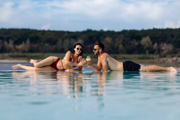 Couple enjoying their vacation and each other's company at a resort pool with cocktails. Concept...