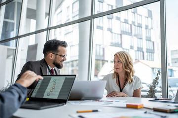 Business people discussing charts on laptop in office meeting