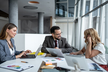 Businesspeople working together on laptops in modern office