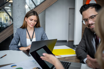 Business team working together on project using laptop and tablet in modern office