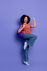 Joyful young woman celebrating success with casual fashion and bright smile standing against a...