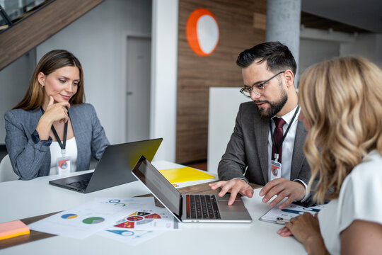 Business team analyzing data on laptop in modern office