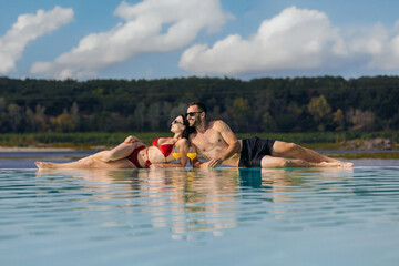 Couple enjoying their vacation and each other's company at a resort pool with cocktails. Concept...