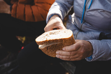Close up of a man hands breaking a slice of salami during a peaceful outdoor break. Man is holding snack in the hands in Beskydy mountains