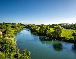 Fototapeta premium Serene river flowing through a lush landscape under a vibrant sky