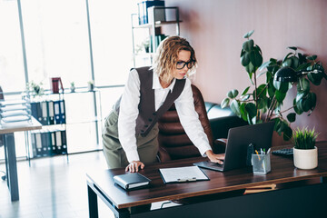 Confident businesswoman wearing formal attire working on laptop in an elegant office environment...