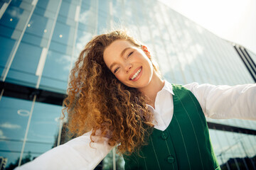 Confident young businesswoman in green formalwear outdoors showcasing a vibrant smile in front of a...