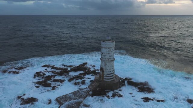 Dramatic sunset illuminating powerful waves striking rocky Mangiabarche 