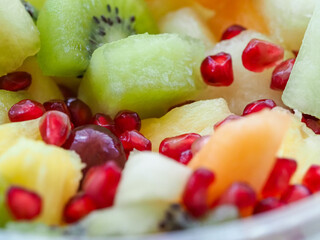 A bowl of fruit with kiwi, pomegranate, and pineapple