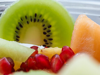 A kiwi is cut in half and placed on top of a bowl of fruit