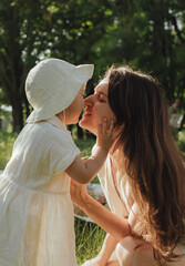 Happy young mother playing with her baby on the grass in a sunny park. Family bonding, early...