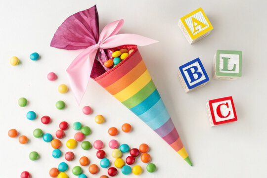 Bunte Schult&uuml;te mit S&uuml;&szlig;igkeiten und ABC-W&uuml;rfeln auf wei&szlig;em Hintergrund