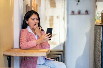 Shocked businesswoman reading unbelievable news on smartphone in cafe