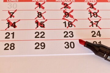 Calendar with crossed-out dates and one circled day, next to a marker. Concept of countdown,...