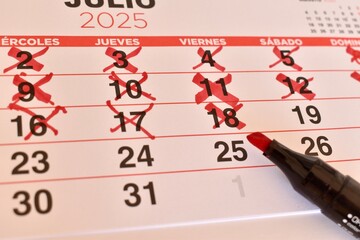 Close-up of Spanish calendar with days marked in red. Represents schedule, deadline, and upcoming...