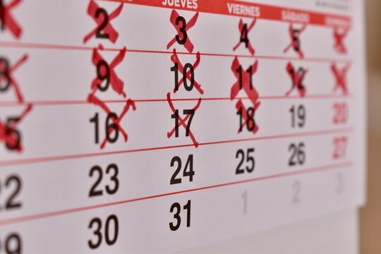 Close-up of Spanish calendar with days marked in red. Represents schedule, deadline, and upcoming events.