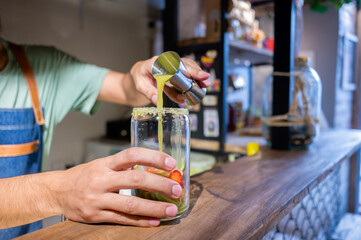 Bartender pouring juice into glass with strawberries and ice at restaurant bar