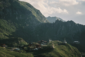 Serene mountain landscape with small houses nestled in the valley. Lush green hills and rocky peaks...