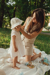 Happy young mother playing with her baby on the grass in a sunny park. Family bonding, early...