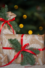 Close up of gift boxes packed in craft paper  decorated with fir branches under the christmas tree....