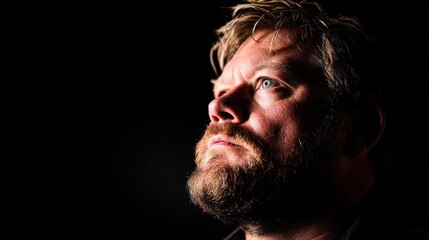 Fototapeta premium Portrait of a man with a beard and intense expression against a dark background