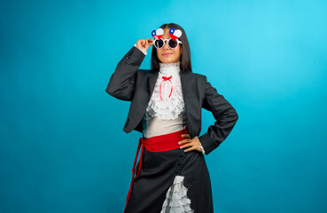 Chilean woman wearing traditional huasa clothing and chilean flag glasses posing on blue background