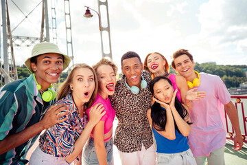 Diverse group of happy young friends enjoying outdoor moments together on a sunny day in a colorful...