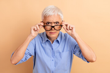 Confident Senior Businesswoman Looking Up with Glasses on Beige Background Promoting Professional...