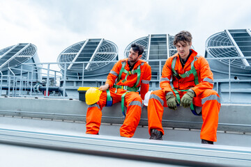Two engineers or technician workers sit and relax together after finish their work on rooftop of...