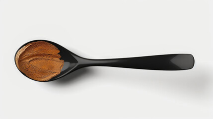 Overhead view of shiny spoon holding vibrant sauce on pale white-gray food design surface
