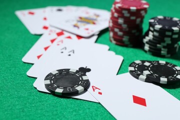 Casino chips and playing cards on green table, closeup