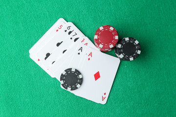 Casino chips and playing cards on green table, flat lay