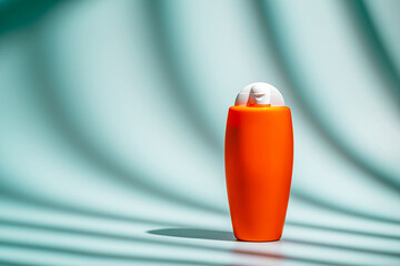 Sunscreen spf orange bottle on light blue background. horizontal layout, clean and minimal style,...