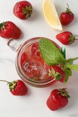 Refreshing drink with strawberries, ice and mint on white table, flat lay