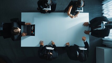 Top down aerial view of diverse data analysts wearing VR headset and stand around table while using...
