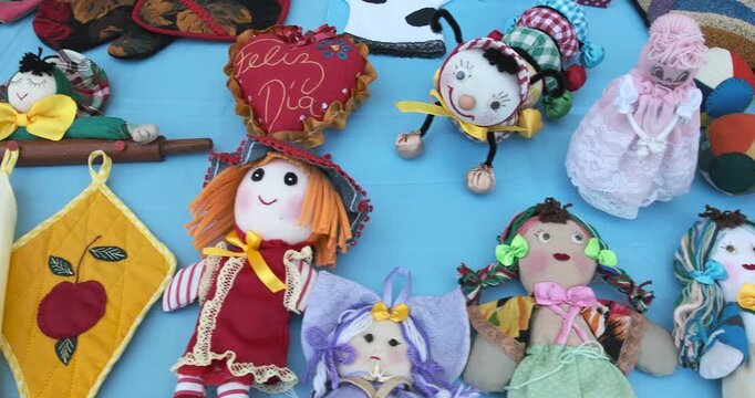 Vibrant handcrafted kitchen textiles including dolls and potholders spreading cheerful colors across light blue fabric surface