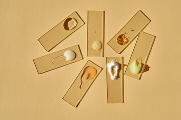 Textures of cosmetic products in a chaotic manner on a beige background.