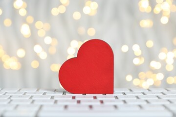 Online dating site. Decorative heart on computer keyboard against blurred lights, closeup. Bokeh...