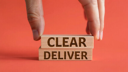 Fingers carefully place wooden blocks spelling out the words clear and deliver on a vibrant coral background