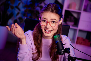 Young female blogger recording podcast at home in a casual setup with professional microphone and...