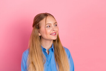 Smiling young girl with long blonde hair wearing a blue shirt against a pink background, radiating...