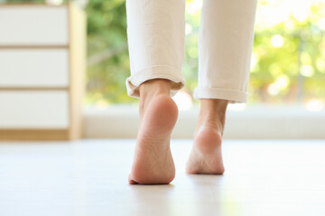 Woman walking on warm floor indoors, closeup. Heating system