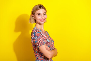 Portrait of a young smiling woman wearing a patterned top against a vibrant yellow background,...