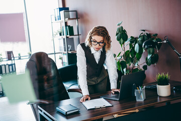 Charming businesswoman at her desk in a modern office, focused on professional paperwork and tasks
