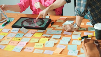 Close up of smart manager hand pointing at tablet display logo at meeting table with sticky notes...