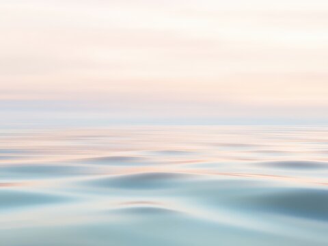 Serene expanse of water reflecting soft hues from the sky, creating a calm and peaceful mood in blurred motion