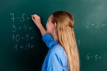 Preteen girl solving math equations on a classroom blackboard emphasizing curiosity and educational...